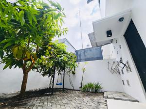 a white building with a tree in front of it at Flo's Transit Home in Manado
