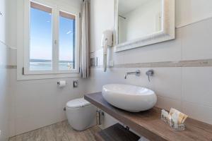 a bathroom with a sink and a toilet and a window at Locanda Stravedo in Pellestrina
