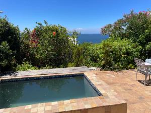 a swimming pool with a table and a chair and the ocean at Oceanview Sunrise Beach Villa in Rocklands +7 photos