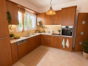 a kitchen with wooden cabinets and a sink at Casa Rosa Ammoudia in Ammoudia