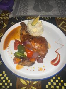 a plate of food with chicken and vegetables on a table at Tangi Elephant Camp in Pakwach East +18 photos