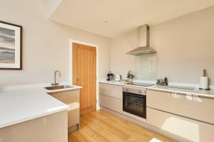 a kitchen with white counters and a sink and a stove at Host & Stay - Stille House in Beadnell