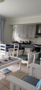 a living room with white chairs and a table and a kitchen at Point Village Accommodation - Alista in Mossel Bay