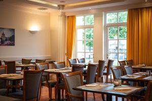 a dining room with tables and chairs and windows at Hotel Villa Geyerswörth in Bamberg