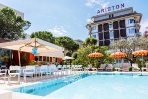 a pool with chairs and umbrellas next to a hotel at Hotel Ariston in Bibione