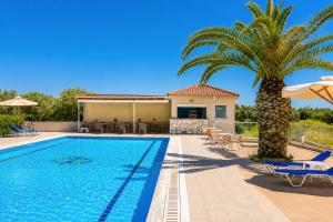 a villa with a palm tree and a swimming pool at Nautilos Hotel in Soullároi