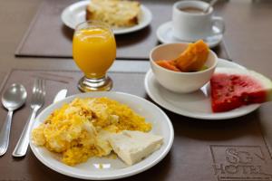 a table with plates of breakfast food and a glass of orange juice at SG Apart Hotel in São Gonçalo do Rio Abaixo
