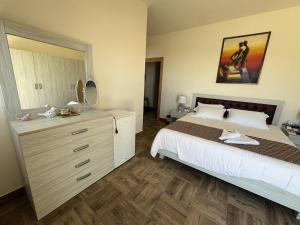 a bedroom with a bed and a dresser with a mirror at Blue House- Peaceful Mountain Escape in Mazraat et Teffâh
