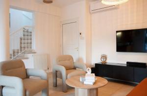 a living room with chairs and a tv and a table at Dream Olea Villa - Ayia Napa in Ayia Napa