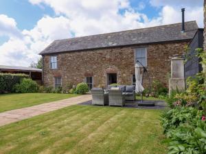 an exterior view of a brick house with chairs and an umbrella at Duke's Barn in Totnes