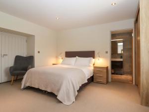 a bedroom with a large bed and a chair at Duke's Barn in Totnes