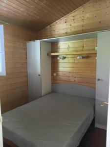 a bed in a room with a wooden wall at Camping Onlycamp Les Bords de Lyonne in Saint-Jean-en-Royans