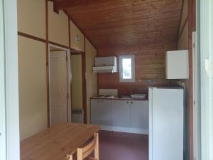 a kitchen with a wooden table and a refrigerator at Camping Onlycamp Les Bords de Lyonne in Saint-Jean-en-Royans
