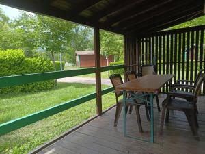 a wooden table and chairs on a porch at Camping Onlycamp Les Bords de Lyonne in Saint-Jean-en-Royans
