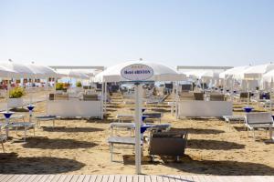 a beach with tables and chairs and umbrellas at Hotel Ariston in Bibione +65 photos