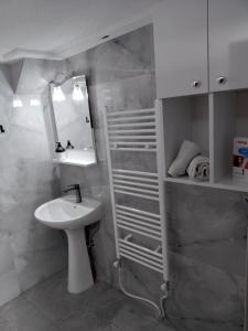 a white bathroom with a sink and a mirror at Apartment Matej in Kruševo