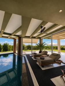 an empty house with a swimming pool with lounge chairs at GF Luxury Villa with indoor pool -Afytos in Afitos