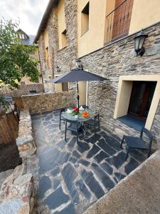 a stone patio with a table and an umbrella at CASA CON ENCANTO ESTERRI in Esterri d'Àneu