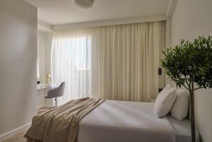 a bedroom with a white bed and a window at Civitel Attik Rooms & Suites in Athens