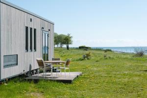 a table and chairs on a deck next to a trailer at Tiny Seaside - Skarrev in Aabenraa