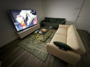 a living room with a couch and a flat screen tv at Aries de Baldock in Canterbury