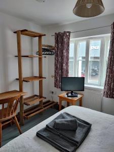 a bedroom with a bed and a desk with a monitor at The Courtyard Hideout in Hereford