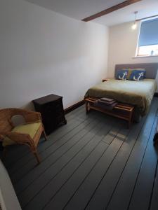 a bedroom with a bed and a chair in a room at The Courtyard Hideout in Hereford