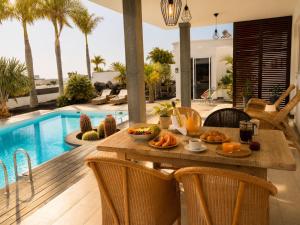 an outdoor dining area with a table and a pool at Villa Claus - Private Pool Oasis in Puerto Calero in Puerto Calero