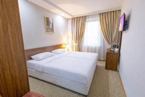 a hotel room with a white bed and a television at Gyumri Hotel in Gyumri