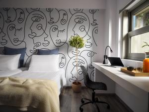 a bedroom with a bed and a desk with a laptop at Civitel Attik Rooms & Suites in Athens +61 photos
