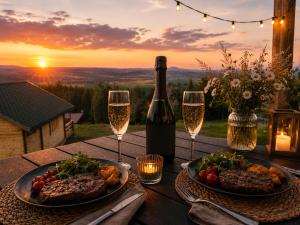 a table with two plates of food and a bottle of wine at Huberkowe Domki in Swiecko +28 photos