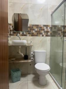 a bathroom with a toilet and a sink at Casa espaçosa em Itacimirim com piscina e churrasqueira! in Camaçari +13 photos