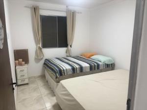 a small bedroom with a bed and a window at Casa espaçosa em Itacimirim com piscina e churrasqueira! in Camaçari