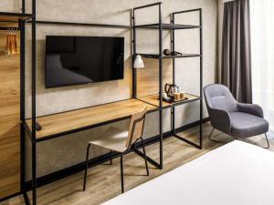 a room with a desk and a chair and a television at ibis London Sutton Point in Sutton