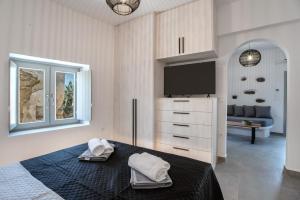 ein Schlafzimmer mit Fernseher und Bett mit Handtüchern in der Unterkunft Næxon in Vívlos