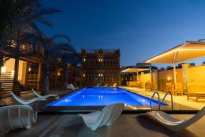 a swimming pool with white chairs and a building at Amun Dahab Hotel in Dahab