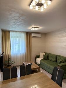 a living room with a green couch and a table at Villa Moste Ljubljana - Modern apartments with Pool, EV station & free parking in Ljubljana