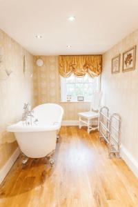 a bathroom with a white tub and a chair at Ormesby Manor House & The Shepherds Huts & Well Lodge in Ormesby Saint Michael +55 photos
