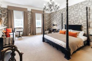 a bedroom with a four poster bed and a chandelier at Ormesby Manor House & The Shepherds Huts & Well Lodge in Ormesby Saint Michael