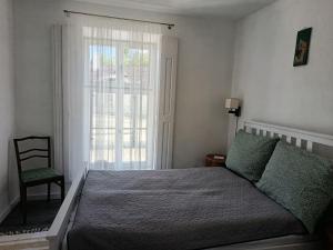 a bedroom with a bed and a chair and a window at Tornác Vendégház in Diszel