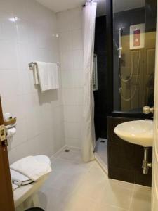a white bathroom with a shower and a sink at Hostal Paraíso Vip in Portoviejo