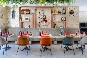 a dining room with tables and chairs and a clock at Hôtel La Solitude in Lourdes