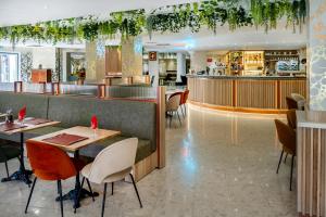 a restaurant with tables and chairs and a bar at Hôtel La Solitude in Lourdes