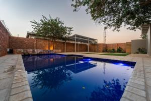 a swimming pool in front of a brick building at The Pods Victoria Falls in Victoria Falls