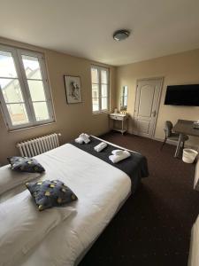 a bedroom with a large bed with two pillows at Logis Hôtel Au Moyne de Saire in Réville