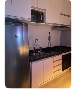 a kitchen with a stainless steel refrigerator and a sink at Apartamento Tranquilo e Aconchegante in Carmo do Rio Claro