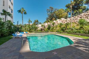a swimming pool in a yard with chairs and a building at Seaside Pool View 3BR Apt with 2 Balconies in Tangier