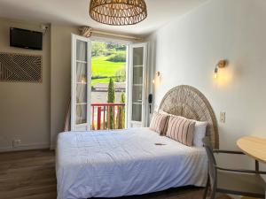 ein Schlafzimmer mit einem Bett, einem Tisch und einem Fenster in der Unterkunft Hôtel Juantorena in Saint-Étienne-de-Baïgorry