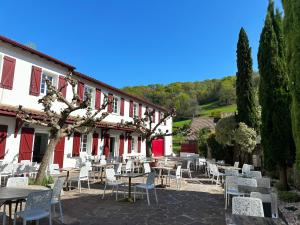 Eine Gruppe von Tischen und Stühlen vor einem Gebäude in der Unterkunft Hôtel Juantorena in Saint-Étienne-de-Baïgorry