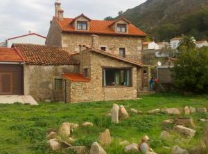 una vieja casa de piedra con una persona parada frente a ella en Casa Rural Romanejo, en Cabezabellosa